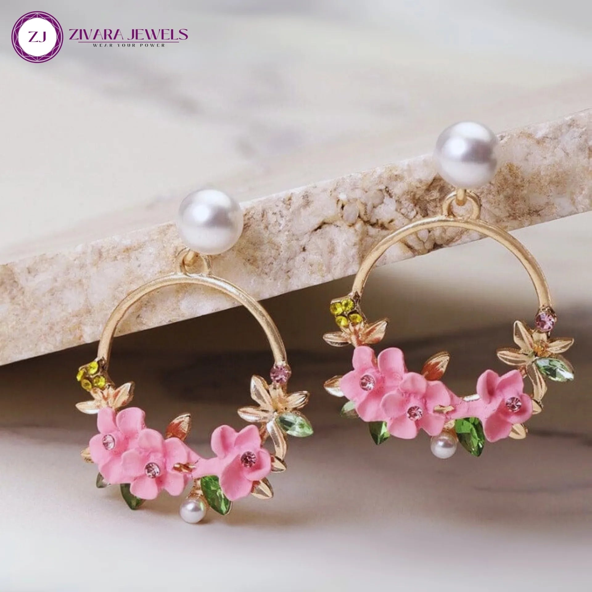 Gold hoop earrings with pink floral and pearl details on a light background