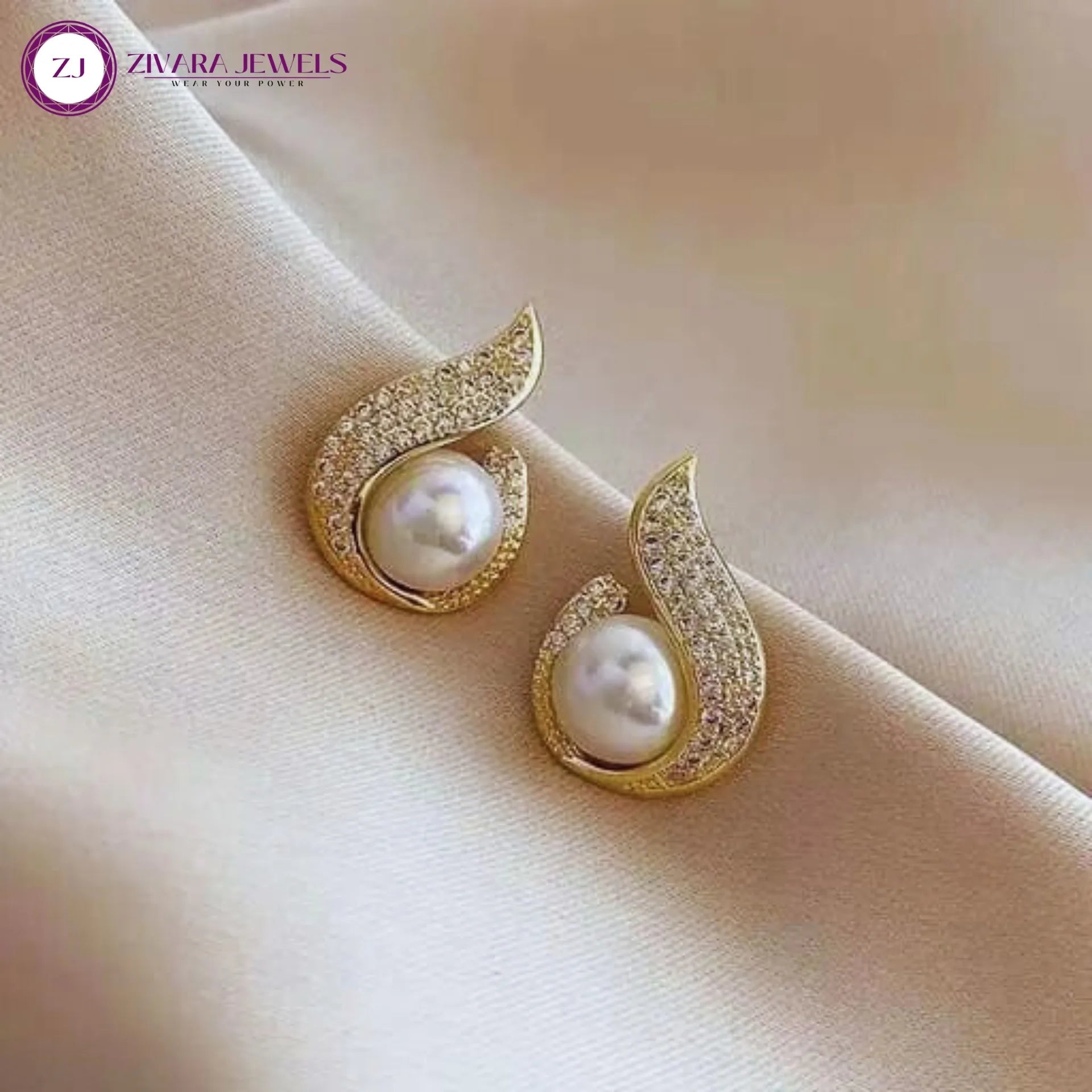 Gold earrings with pearls on a beige fabric background, featuring Zivara Jewels logo.