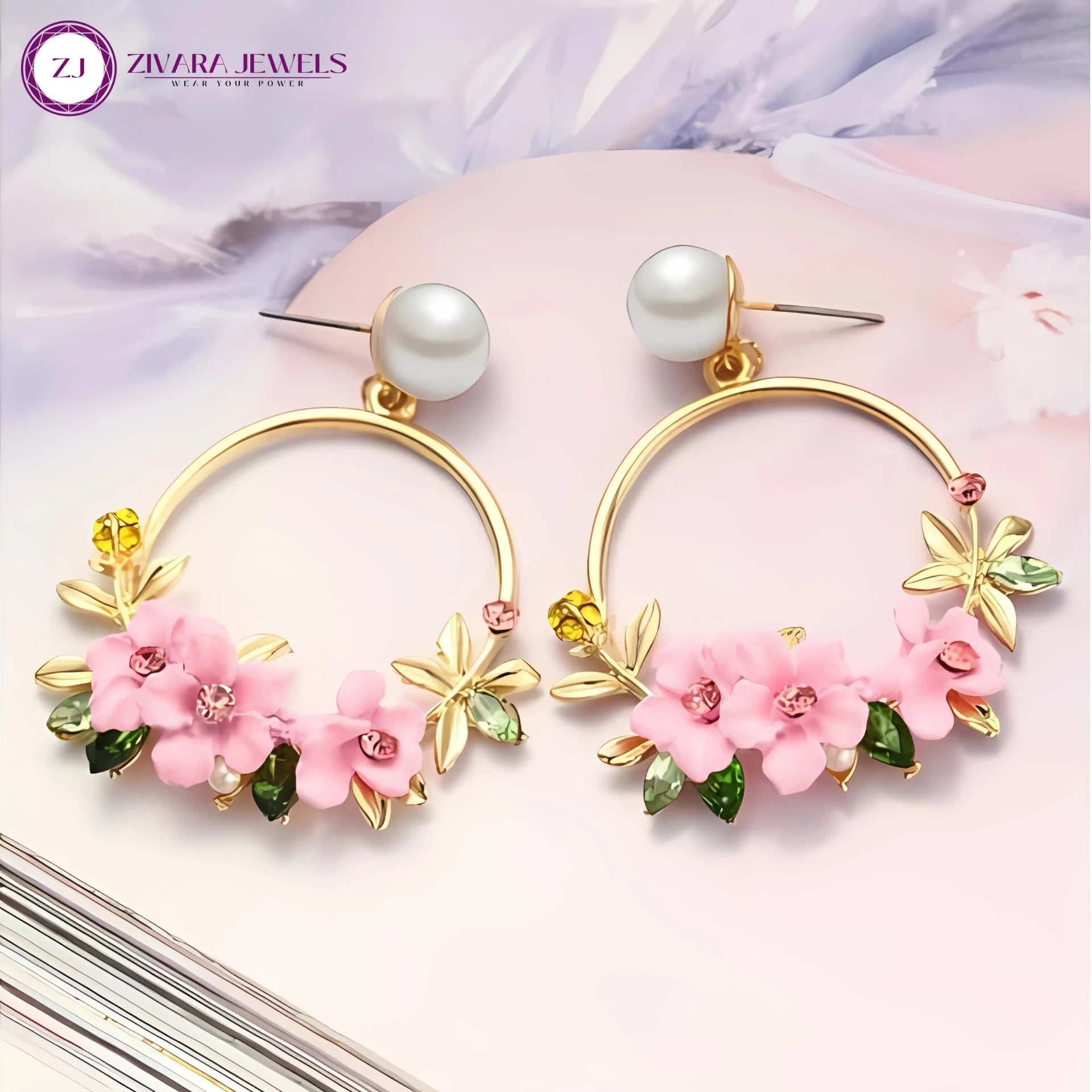 Gold hoop earrings with pink floral designs and pearls on a soft pink background, featuring Zivara Jewels logo.